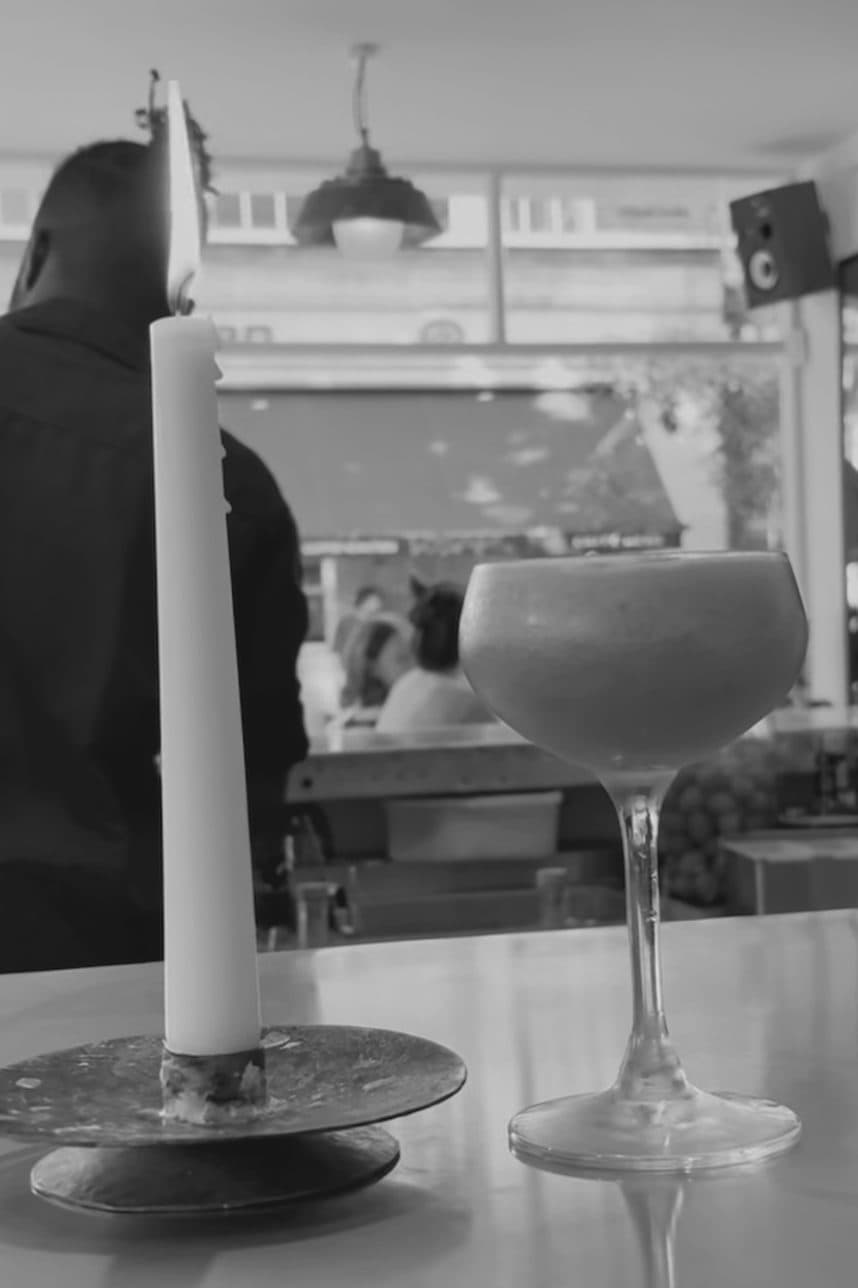 A cocktail and a lit candle on the bar